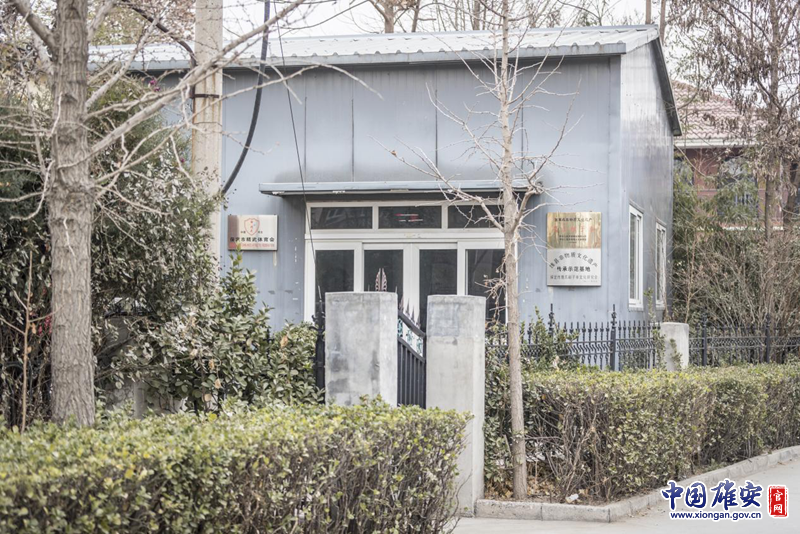 雄安新區雄縣，一間居民房在樹木的遮擋下顯得很不起眼。房子的門邊卻掛著“國家級非物質文化遺產——鷹爪翻子拳”的金色招牌。李鑫 攝